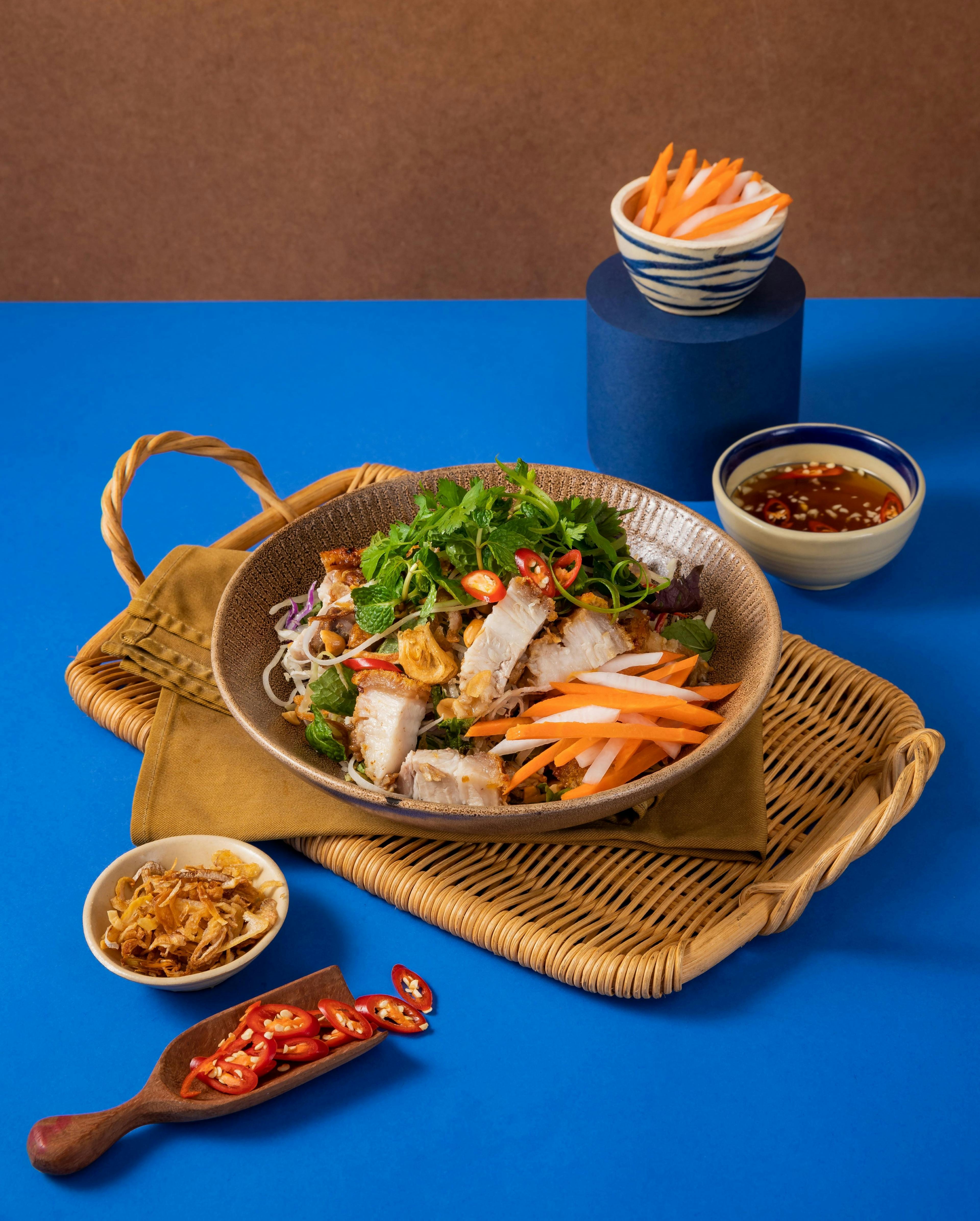 Crispy Roast Pork served with shredded cabbage, pickle, radish, cucumber, herbs, fried shallot, peanut, chilli, and sweet and sour fish sauce.