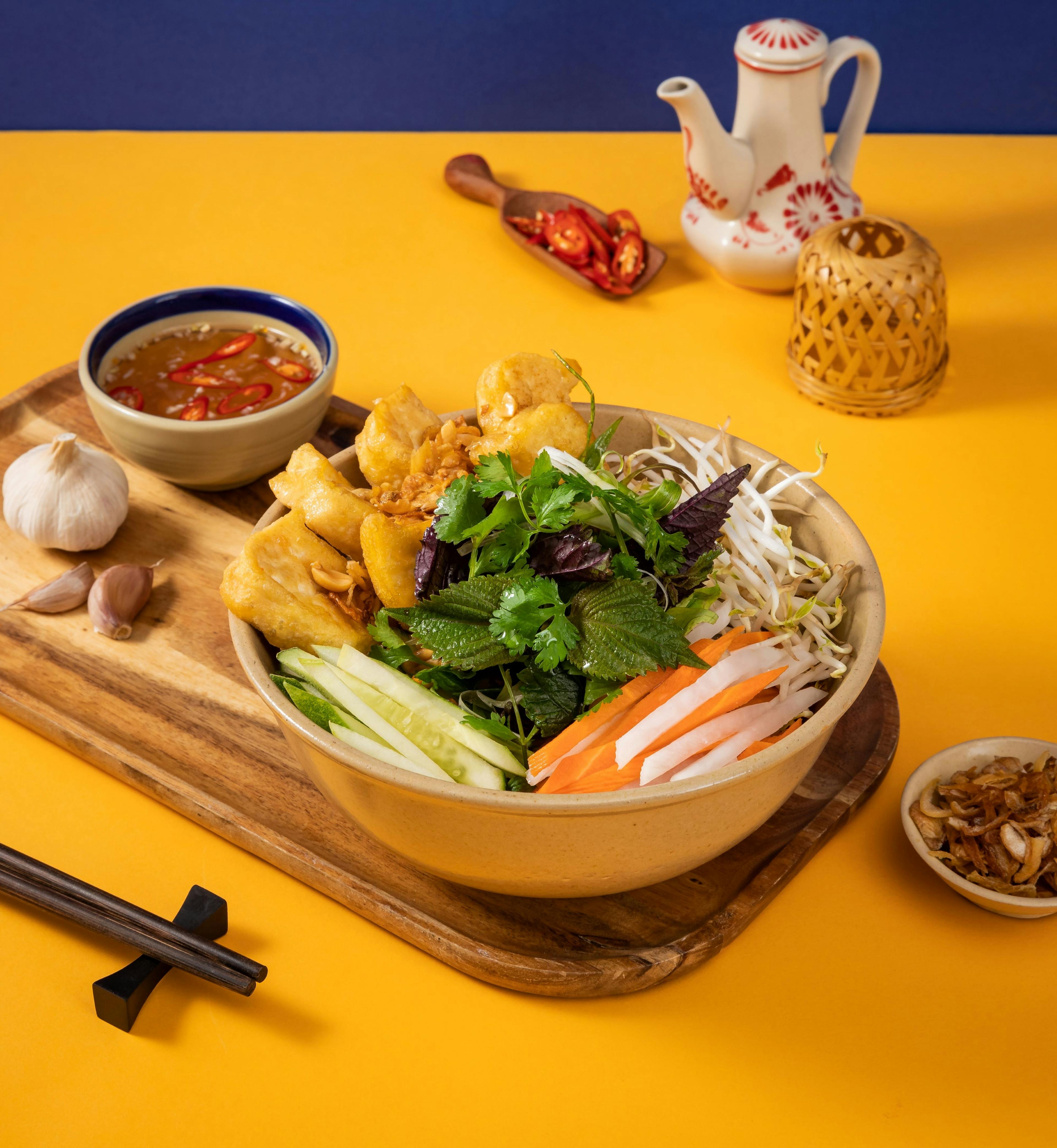 Tasty Tofu served with shredded cabbage, pickle, radish, cucumber, herbs, fried shallot, peanut, chilli, and sweet and sour vegan fish sauce.